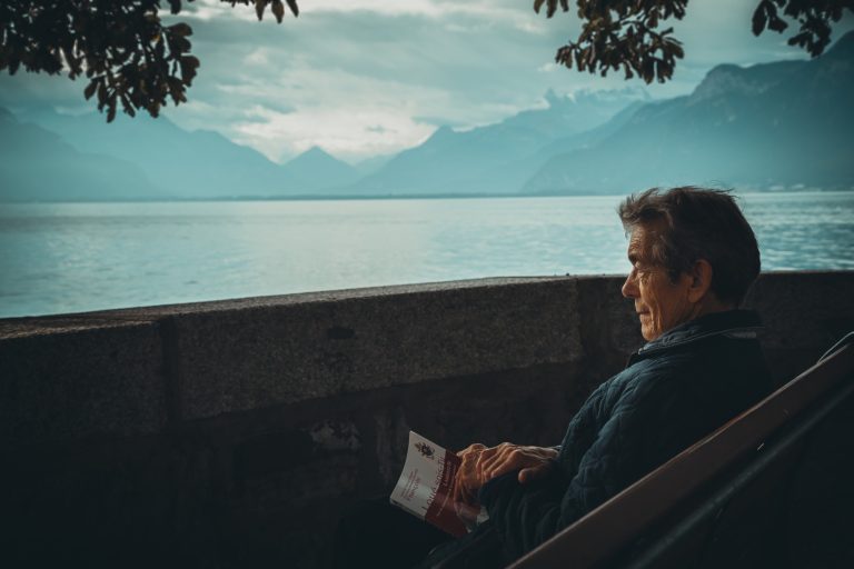 Man reading book overlooking lake
